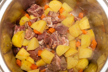 View of the inside of a pot cooking veal with potatoes and carrots