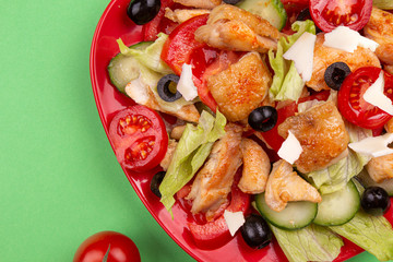 Vegetable and meat salad of mozzarella, cheese, olives, chicken, cucumber, tomatoes on green background. Low carb dietary food. Top view. Copy space