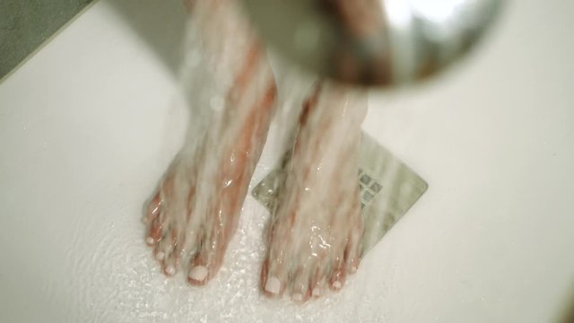 Young attractive woman taking a shower in bathroom. Beautiful girl washing her body under a shower. Slow motion. HD