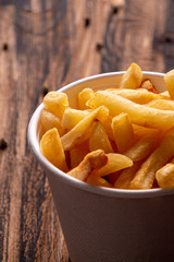 White paper bowl of french fries chips potato on wooden table