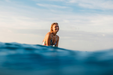 Attractive surfer girl on a surfboard in ocean.