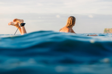 Attractive surfer girl on a surfboard in ocean.