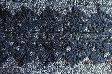 Black lace on grey melange woolen fabric from above