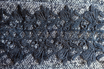 Delicate black lace on grey melange woolen fabric from above