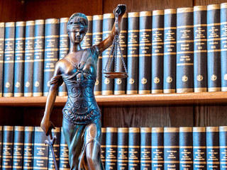 Justitia Figur Gerechtigkeit Statue vor einem Bücherregal