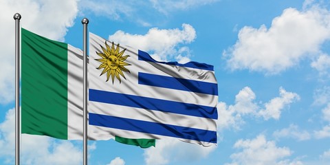 Nigeria and Uruguay flag waving in the wind against white cloudy blue sky together. Diplomacy concept, international relations.