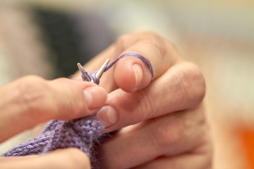 Woman is knitting a blue warm sweater. A hobby of elderly woman is knitting. Closeup view of...