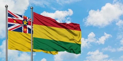 Niue and Bolivia flag waving in the wind against white cloudy blue sky together. Diplomacy concept, international relations.