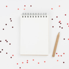 Notebook, pencil on white background with confetti. Merry Christmas, Happy New Year, wish list concept. Top view, flat lay, copy space, mock up, square format