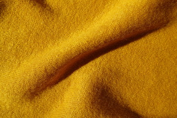 Diagonal fold of mustard yellow knitted woolen fabric