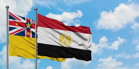 Niue and Egypt flag waving in the wind against white cloudy blue sky together. Diplomacy concept, international relations.