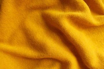 Orangey yellow knitted woolen fabric in soft folds