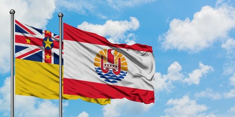 Niue and French Polynesia flag waving in the wind against white cloudy blue sky together. Diplomacy concept, international relations.