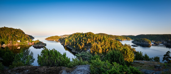 Panorama of the Norwegian coastline bay with lots of green forest at dusk