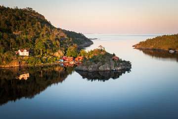 Sunset at the Norwegain coast with beautiful reflection of the red houses in the bay
