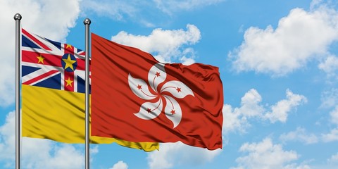 Niue and Hong Kong flag waving in the wind against white cloudy blue sky together. Diplomacy concept, international relations.