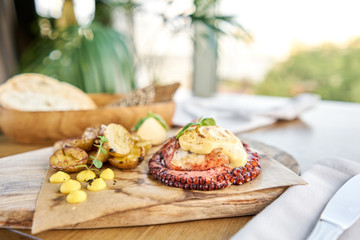 Roasted octopus BBQ with Baked potato. Wooden plate. Restaurant menu