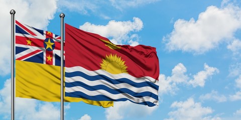 Niue and Kiribati flag waving in the wind against white cloudy blue sky together. Diplomacy concept, international relations.