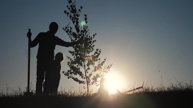 happy family of farmers a silhouette concept slow motion video. dad son and daughter children plant and water the tree outdoors in lifestyle the park. happy family little girl and boy works in garden