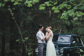 Fototapeta na wymiar bride and groom embracing near a retro car outdoors
