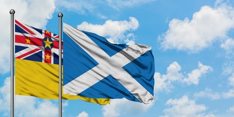 Niue and Scotland flag waving in the wind against white cloudy blue sky together. Diplomacy concept, international relations.