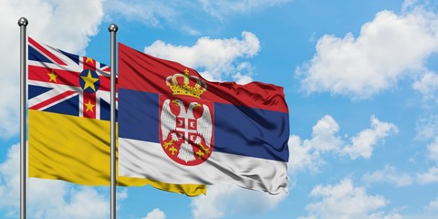 Niue and Serbia flag waving in the wind against white cloudy blue sky together. Diplomacy concept, international relations.