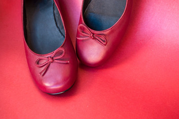 Stylish female flat shoes in dark red color on dark red background with copyspace. Beauty and fashion concept.