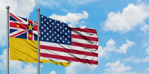 Niue and United States flag waving in the wind against white cloudy blue sky together. Diplomacy concept, international relations.