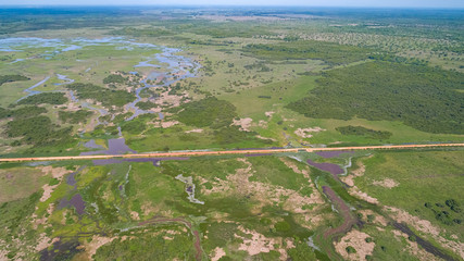 Aerial view of Transpantaneira dirt road crossing a lagoon over a small bridge in the typical landscape of North Pantanal Wetlands, Mato Grosso, Brazil