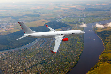Passenger plane in flight. The plane flies against a background of green plain and river.