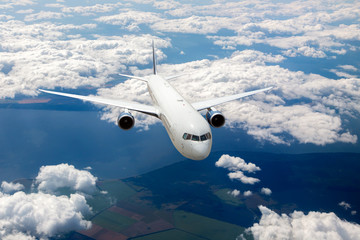 Aircraft in flight. The passenger plane flies high above the clouds and earth. Front view of airplane.