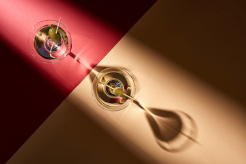 Top view of martini with olives on red and beige background
