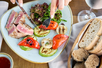Lunch in a restaurant, a woman eats Medium rare tuna with lettuce and hot sauce. Restaurant menu