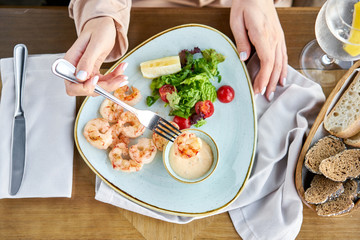 Grilled Argentine shrimp with mango-jalapeno sauce. Lunch in a restaurant, a woman eats delicious and healthy food. Delicious fresh seafood prawns with fresh vegetables and lime. Cream sauce