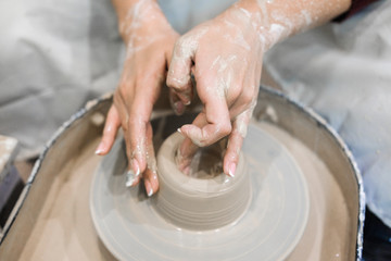 Sculptor woman makes a cup on a potters wheel.