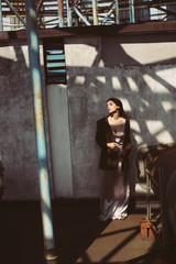 Obraz premium attractive woman posing in silk dress and brown jacket on roof