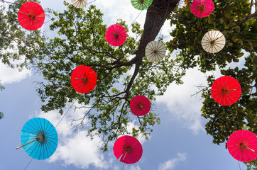 Picture of sky-hanging umbrellas with trees on the background for Loi Krathong festival