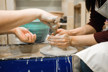 Sculptor woman makes a cup on a potters wheel.