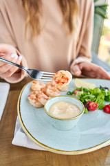 Grilled Argentine shrimp with mango-jalapeno sauce. Lunch in a restaurant, a woman eats delicious and healthy food. Delicious fresh seafood prawns with fresh vegetables and lime. Cream sauce