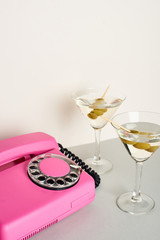 Pink retro telephone with martini cocktails on white background