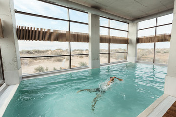 Human relaxing in luxury swimming pool in modern hotel