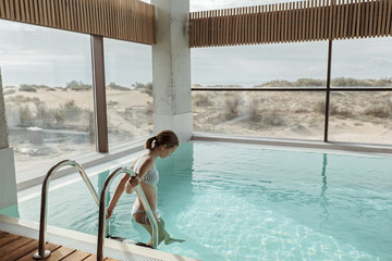 Girl relaxing in luxury swimming pool in modern hotel