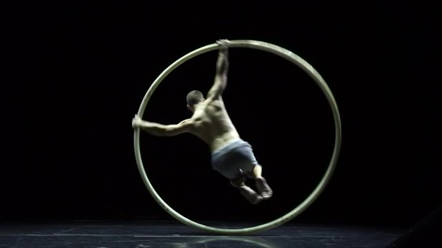 Muscular circus artist in the Cyr Wheel doing difficult tricks slow motion. Concept of concentration and balance