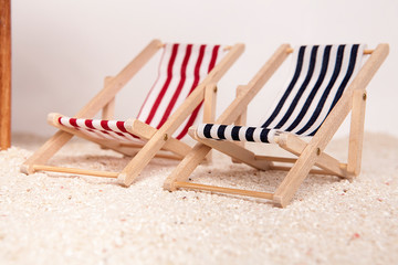 Fototapeta na wymiar Toy chaise longue on sandy beach on white background. Relaxation concept.