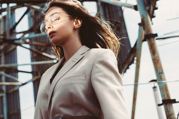 Fototapeta premium Fashionable girl posing with closed eyes in beige suit and beret on urban roof
