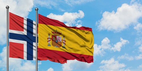 Norway and Spain flag waving in the wind against white cloudy blue sky together. Diplomacy concept, international relations.