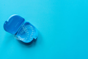 close up top view of dental aligner retainer (invisalign) on blue color background with copy space at dental clinic for beautiful teeth treatment course concept - obrazy, fototapety, plakaty
