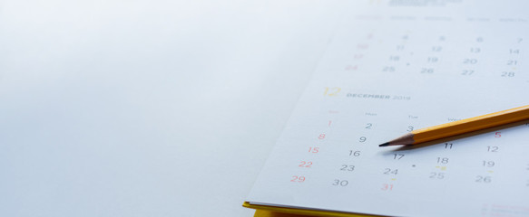 close up side view on yellow pencil over white  calendar schedule background to make appointment meeting or manage timetable each day for planning work and life concept