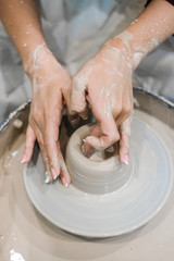 Sculptor woman makes a cup on a potters wheel.