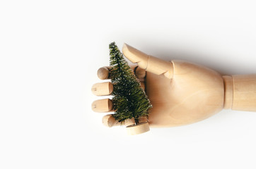 Christmas artificial tree on a wooden stand in the mock up of a hand. The concept of New Year's preparations and sales. Environmental Protection. Zero waste. Minimalist background